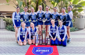 Cheerleading team in blue and white uniforms posing with trophy and medals.