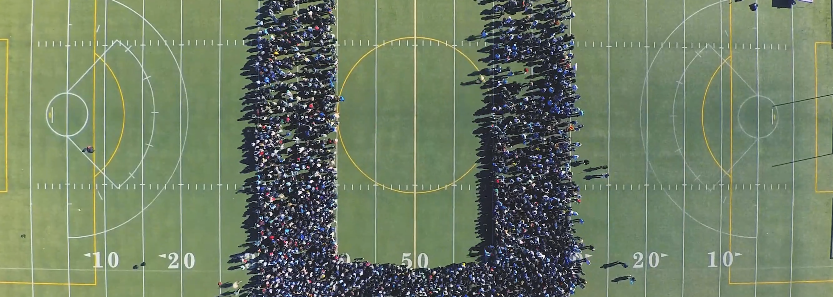 overhead shot of field, people forming "U"