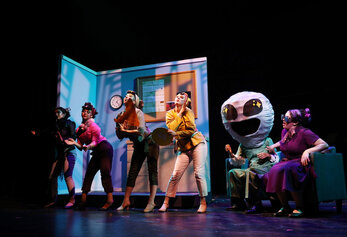 Students perform a stylized scene from University High School’s Dreamland, featuring an alien character and colorful costumes.