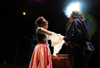 Two students share an emotional moment in University High School’s “Romeo & Juliet,” holding hands under a spotlight.